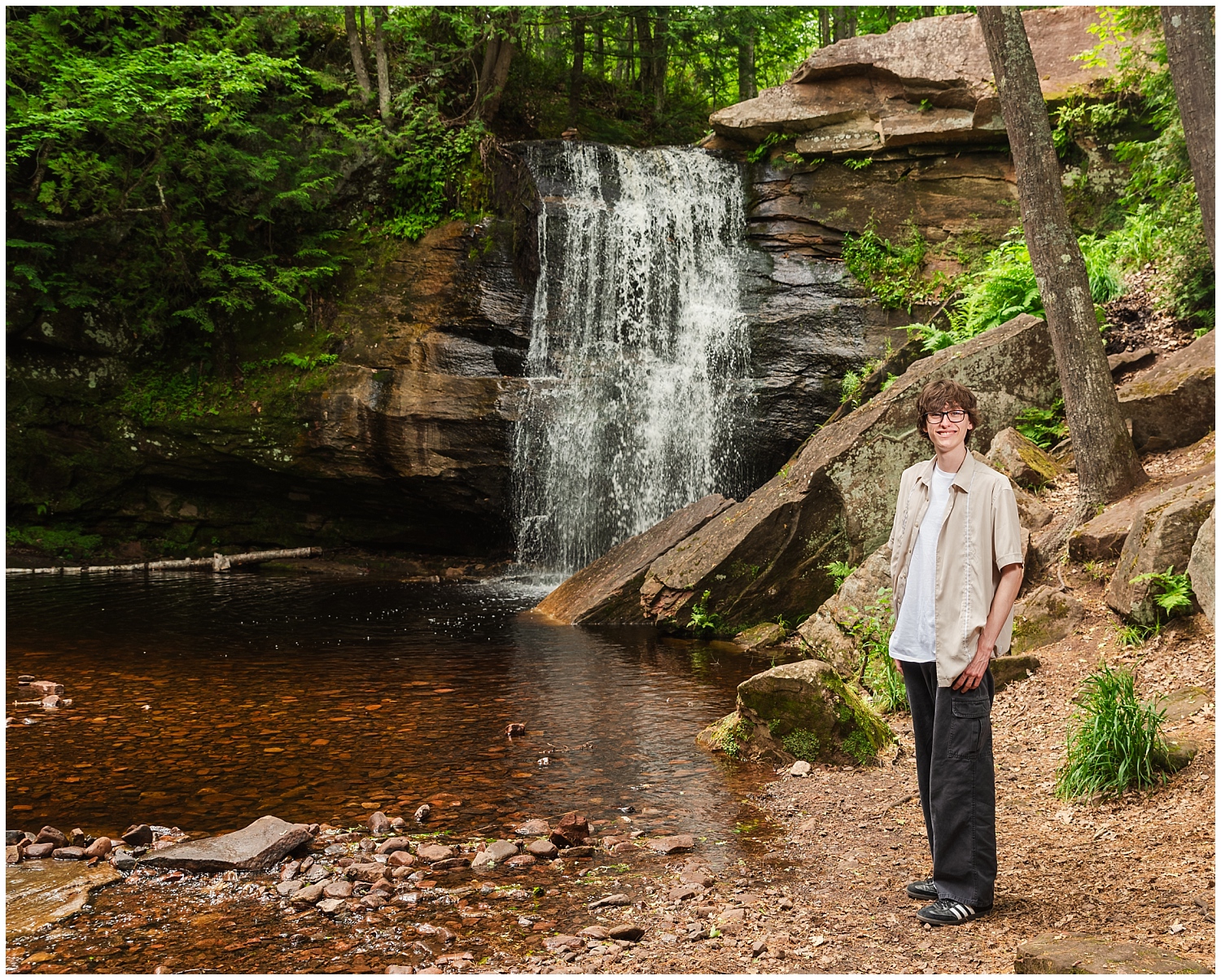 boy stands in front of popular keweenaw waterfall middle hungarian falls for senior pictures