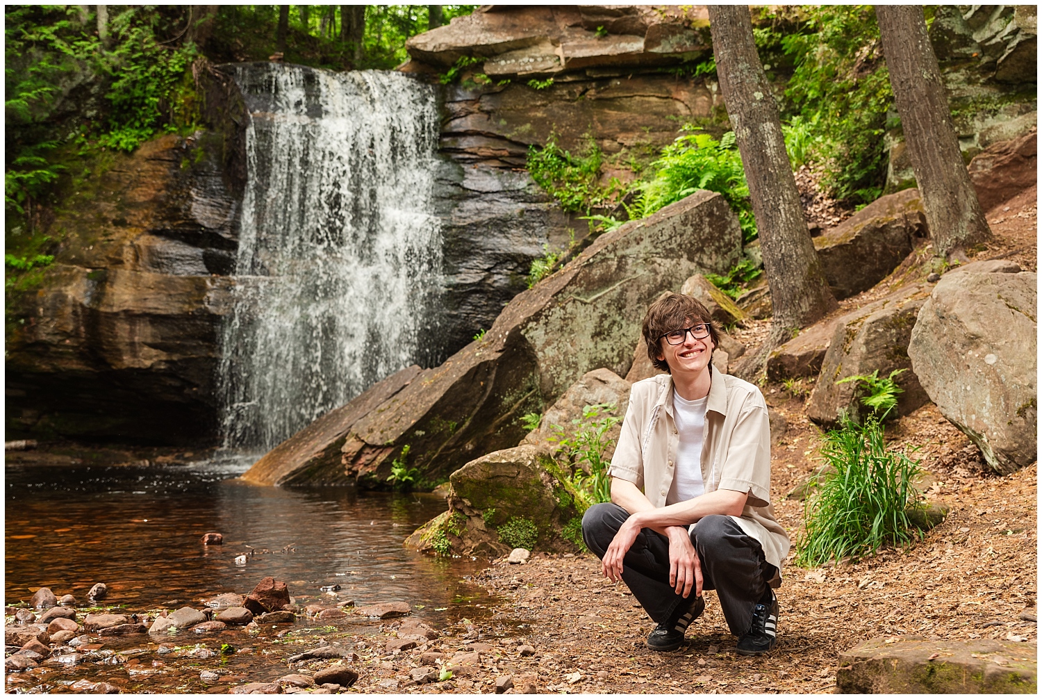boy kneels in front of keweenaw waterfall middle hungarian falls for senior portrait