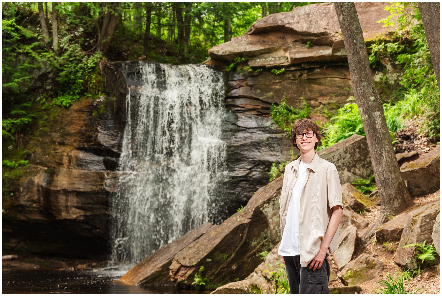 boy stands in front of keweenaw hungarian falls waterfall during senior pictures