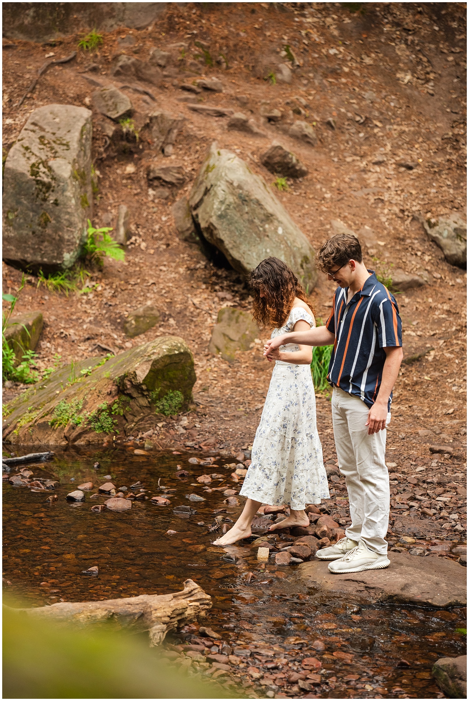 man and woman test the water near waterfall in hubbell michigan
