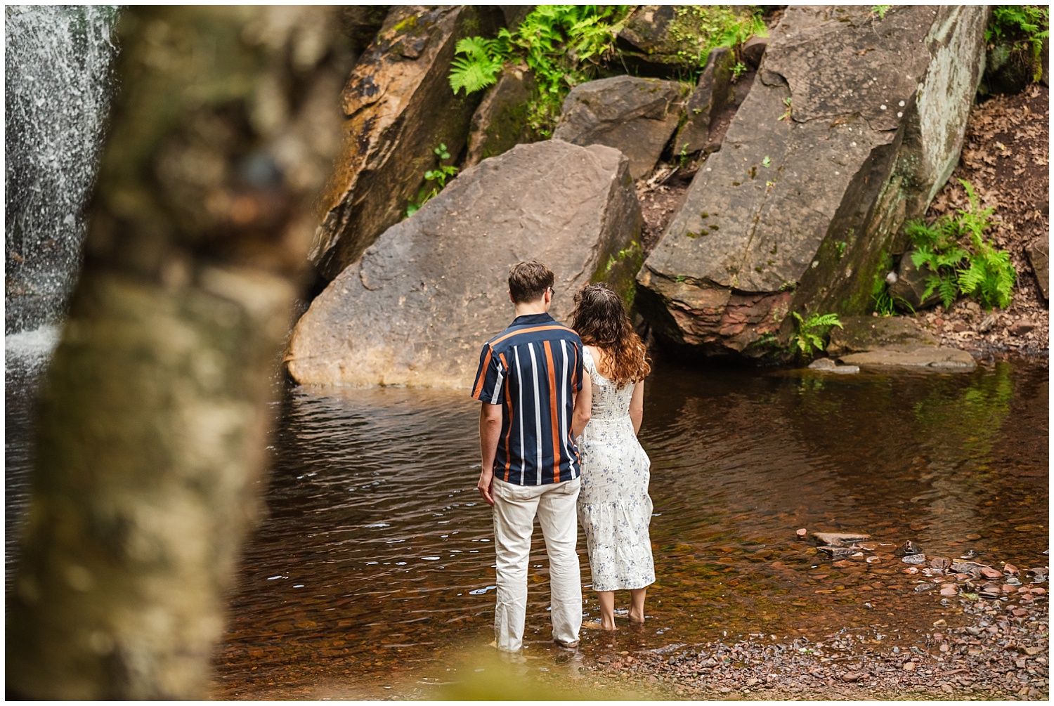 couple stands at base of hungarian falls waterfall in keweenaw peninsula upper peninsula