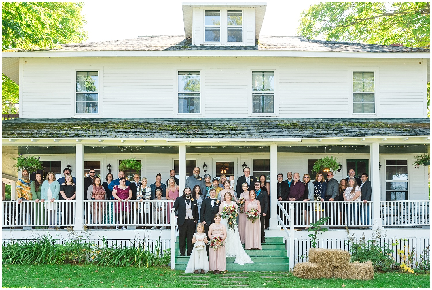 picture with all wedding guests on porch of chamberlin ole forest inn curtis michigan